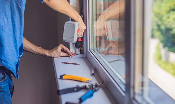 man drilling into window sill