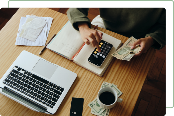 man calcuating financials with phone calculator while holding money