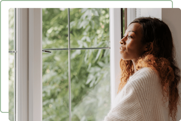 woman looking out of a window with trees on the outside