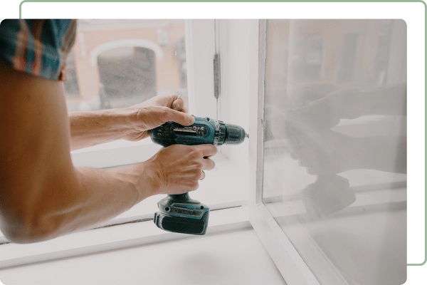 closeup of a man installing a swinging window with a drill